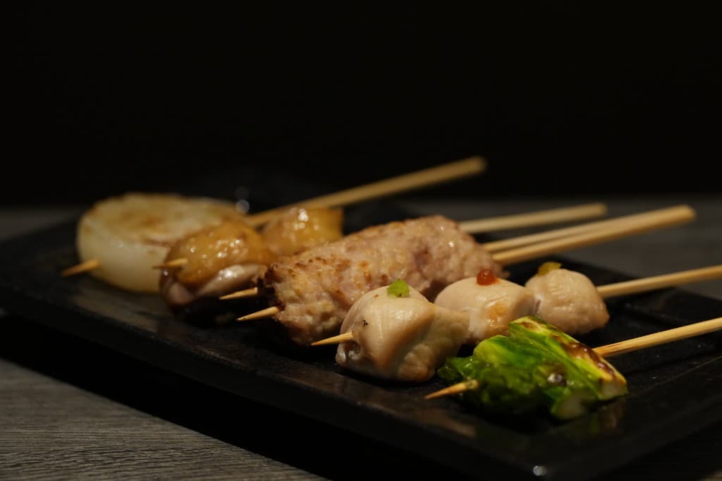 黒い長皿に並んだ焼き鳥の盛り合わせ